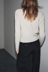 Chaqueta de lana 100% color gris claro, con cuello redondo, manga larga y cierre frontal con botones.