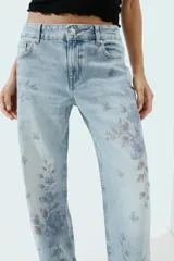 Jeans Z1975 de tiro medio y pernera recta con diseño de cinco bolsillos, cierre frontal con cremallera y botón, y delicado estampado floral en tonos azules.