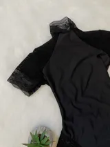 Body negro de lycra entallado con detalles de microtul y encaje, cuello alto y espalda descubierta.