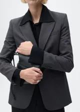 Chaqueta de corte recto con estampado de micro pata de gallo, cuello con solapa y cierre frontal de botones. Presenta mangas largas con puños abotonados, bolsillos delanteros con solapa y abertura posterior en el bajo.