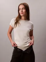 Remera Calvin Klein de punto de algodón regenerativo, color beige melange, de corte regular y manga corta con vuelta. Presenta cuello redondo y sutil logo bordado en el pecho.
