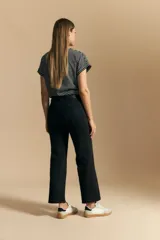 Jean de corte recto y tiro medio, confeccionado en denim elastizado de color negro. Presenta un diseño clásico con cierre de botón y cremallera, bolsillos laterales y traseros, y ruedo con terminación deshilachada.