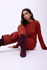 Pantalón recto de tiro medio con largo al tobillo, confeccionado en tela con estampa geométrica abstracta en tonos rojizos y marrones.