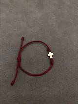 Set de tres pulseras ajustables de cordón con detalles religiosos. Incluye una pulsera roja con cruces, una pulsera marrón trenzada con cruz y medallas, y una pulsera verde con medalla colgante.