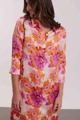 Vestido camisero midi con estampado floral en tonos naranja, rosa y fucsia. Tiene cuello camisero, mangas 3/4 y aberturas laterales.
