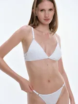 Bralette de encaje color beige con diseño triangular, breteles ajustables y cierre posterior con broche. Cuenta con copas removibles y detalle de pequeño lazo en el centro.
