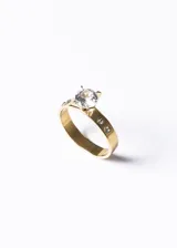 Anillo dorado de acero quirúrgico con circonia central y pequeñas circonias engarzadas en el aro.