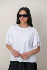 Remera de algodón color blanco, con cuello redondo y mangas cortas holgadas que presentan detalles de encaje broderie.