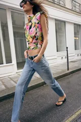 Jeans de tiro medio con corte slim fit, confeccionados en denim azul clásico. Presentan diseño de cinco bolsillos, cierre frontal con cremallera y botón, e incluyen un cinturón negro con hebilla metálica.