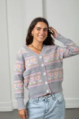 Cárdigan tejido de punto en color gris, con diseño estampado de flores y guardas caladas. Presenta escote en V, cierre frontal con botones y terminaciones acanaladas en puños y ruedo.