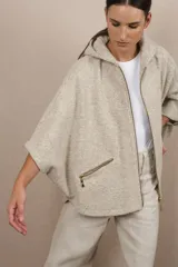 Capa con capucha, cierre frontal y bolsillos laterales con cierre. Diseño amplio y descontracturado, confeccionada en lana fina sin teñir.