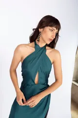 Vestido largo de seda lavada color verde esmeralda, con escote cruzado, falda en capas y flecos negros en el ruedo.