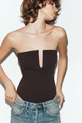 Body de tejido elástico color negro, con diseño strapless, escote recto con abertura frontal y cierre inferior con botones a presión.