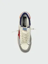 Zapatillas Golden Goose modelo Stardan con diseño tricolor. Presentan cuerpo de cuero blanco con paneles laterales de malla gris, estrella lateral de gamuza roja, puntera de gamuza gris y detalles en azul marino en el talón. Incluyen suela con efecto desgastado característico de la marca.