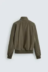 Cazadora de corte relajado color verde militar, con cuello subido, cierre frontal con cremallera y bolsillos laterales con solapa. Presenta puños y ruedo con acabado en rib.