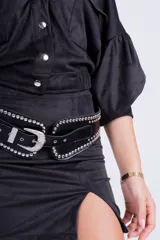 Minifalda negra de gamuza sintética con tajo lateral y cinturón con tachas plateadas.