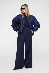 Campera bomber de estilo militar, confeccionada en poliéster con acabado ligeramente satinado. Presenta diseño acolchado, bolsillos frontales, bolsillo utilitario en la manga, puños y cuello acanalados, y cierre frontal con tirador personalizado.