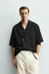 Camisa tipo kimono de corte relaxed fit, color celeste, confeccionada en tejido fluido de viscosa y lino. Presenta cuello con solapas de muesca, manga corta y cierre frontal cruzado con doble botonadura.