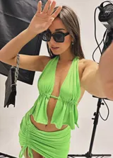 Conjunto de dos piezas compuesto por un top halter con volados y una minifalda ajustada con frunces laterales y tiras regulables.