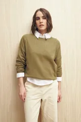 Sweater de punto fino color verde oliva, con cuello redondo y mangas largas. Presenta un diseño con calados delicados en la parte superior y en las mangas, ofreciendo una textura ligera y elegante.