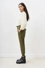 Pantalón tipo babucha de gabardina elastizada, color negro, con cintura elástica ajustable mediante cordón, puños en los tobillos, bolsillos diagonales frontales y bolsillos traseros con solapa y botón.