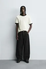 Jeans de denim de algodón color negro, con corte balloon fit relajado desde la cadera y ligeramente estrechado en el bajo. Tiro medio, cinco bolsillos y cierre frontal con cremallera y botón.