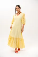 Vestido largo amarillo mantequilla con escote en V, mangas abullonadas y volados en el bajo con detalles de broderie.