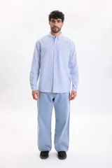Camisa de lino de manga larga con diseño a rayas en color azul claro y blanco, cuello abotonado y cierre frontal de botones.