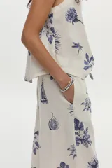 Pantalón de pierna ancha, confeccionado en lino, con cintura elástica con cordón de ajuste y estampado en tonos azules sobre base cruda.