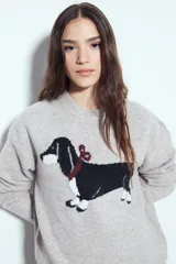 Sweater de punto color gris melange con diseño tejido de un perro salchicha en el frente. Presenta cuello redondo, mangas largas y un corte relajado.