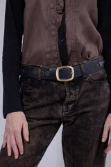 Cinturón de cuero negro con hebilla rectangular de metal dorado y detalles de tachas metálicas circulares grabadas a lo largo de la tira.