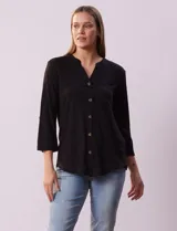 Blusa Ninety color beige con textura, cuello base con escote en V y abertura central con botones. Tiene un bolsillo en el pecho y mangas 3/4 regulables con presilla y botón.