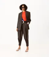 Pantalón de sastre de corte wide leg con diseño de rayas verticales, confeccionado en crepé color gris oscuro. Cuenta con tiro alto, pinzas profundas en el frente y detalle de tira ajustable con botón en el ruedo.