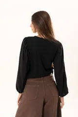Blusa negra de tejido acanalado con mangas largas abullonadas de textura arrugada y puños elásticos.