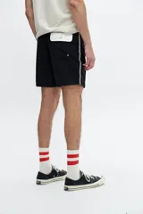 Short de baño negro con cordón ajustable en la cintura y una fina línea blanca en el lateral.