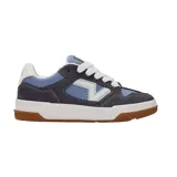 Championes Vans modelo Upland, con diseño de caña baja, confeccionados en una combinación de gamuza gris oscuro y paneles de cuero sintético en tonos azul y blanco. Presentan el logo lateral característico de la marca, suela de goma blanca con base de caucho natural y cordones blancos.