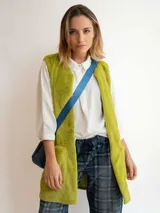 Chaleco largo de piel sintética color blanco, con cuello solapa y dos bolsillos delanteros.