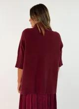Sweater de punto color bordó, con cuello alto y mangas cortas con terminación acanalada.