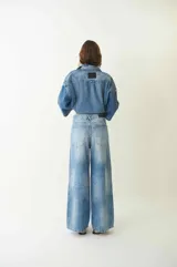 Jean de tiro medio con silueta amplia y corte baggy, confeccionado en denim de algodón con lavado claro desgastado. Cuenta con cierre frontal, botón metálico y bolsillos funcionales.