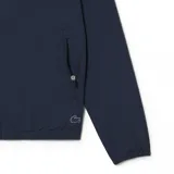 Campera azul marino con capucha y cierre frontal. Presenta el logo de Lacoste en el pecho y en la manga izquierda.