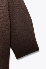 Jersey de punto marrón oscuro, cuello redondo y manga corta, con diseño de punto acanalado y detalles en punto diamante en el torso.