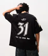 Remera oversized de poliéster calado estilo mesh, color negro con detalles en blanco y dorado, cuello redondo y mangas cortas. Presenta estampa frontal localizada, numeración y estrellas aplicadas en los hombros.