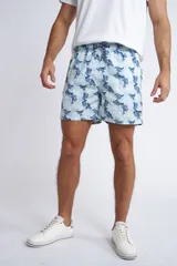 Short de baño con cintura elástica y cordón ajustable, confeccionado en tela ligera de secado rápido. Presenta un estampado botánico integral en tonos amarillos, blancos y azules, con dos bolsillos delanteros y uno posterior.