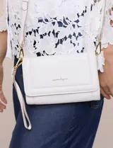 Cartera rectangular estructurada de eco-cuero blanco, con solapa frontal, cierre magnético, logo metálico dorado y correa larga regulable y desmontable.