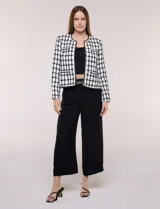 Chaqueta corta de corte estructurado confeccionada en tejido de tweed azul con patrón de cuadros, escote redondo sin solapa, frente abierto, bolsillos falsos y ribetes trenzados con hilos metalizados.