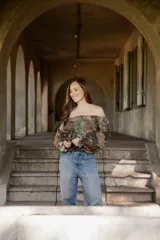 Blusa de lino con diseño off-shoulder, mangas largas amplias y estampado floral en tonos tierra y verdes.