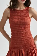 Vestido corto beige sin mangas con cuerpo de nido de abeja elástico y falda corta acampanada con vuelo.