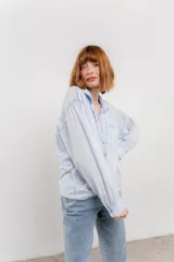 Camisa color crema de algodón con cuello camisero, botones y detalles de encaje en el escote.