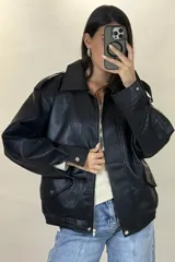 Chaqueta de ecocuero color marrón, de corte oversize, con cuello clásico, cierre frontal metálico, bolsillos laterales con solapa y puños con broches a presión.