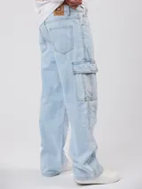 Pantalón de jean celeste claro, estilo cargo, de corte muy ancho (baggy) con múltiples bolsillos laterales.